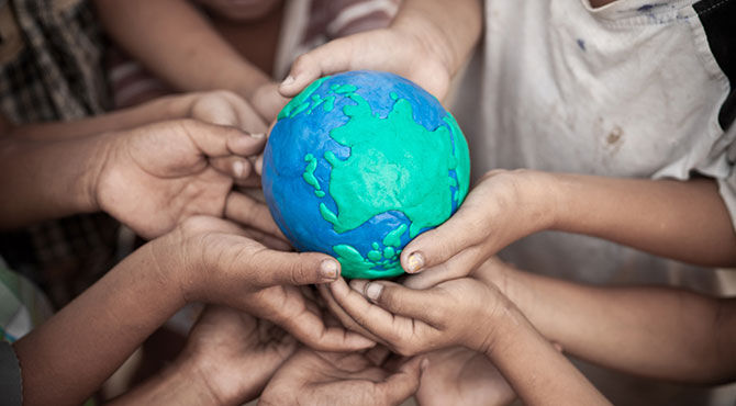 Children's hands cup a globe illustrating an article about the Amos Trust work