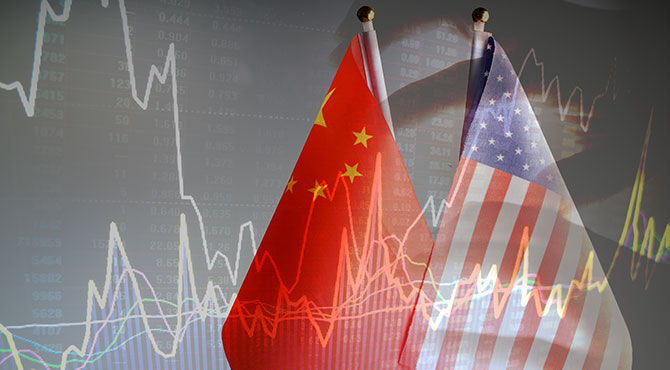 Chinese and American flags over a background showing financial markets