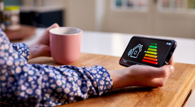 Close Up Of Woman Holding Smart Energy Meter In Kitchen Measuring Energy Efficiency