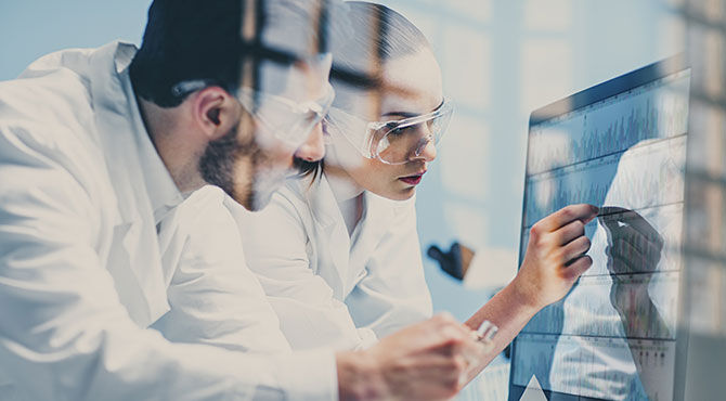 Two researchers study a computer monitor illustrating an article about increased funding for R&D in the UK