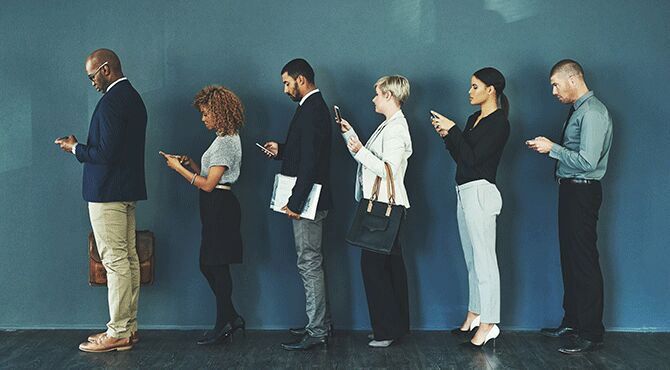 Young workers wait in queue on mobile phones