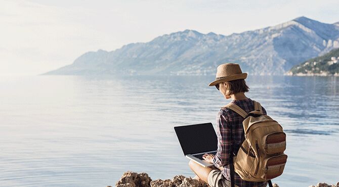 Young woman using laptop by the sea