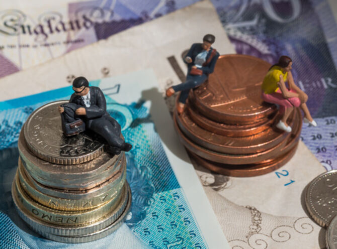 Image of coins and models of people sitting on them to represent gender pay gap